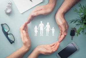 Hands with cut out paper silhouette on table. Family care concept.