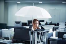 Woman holding an umbrella while working in office