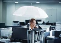 Woman holding an umbrella while working in office