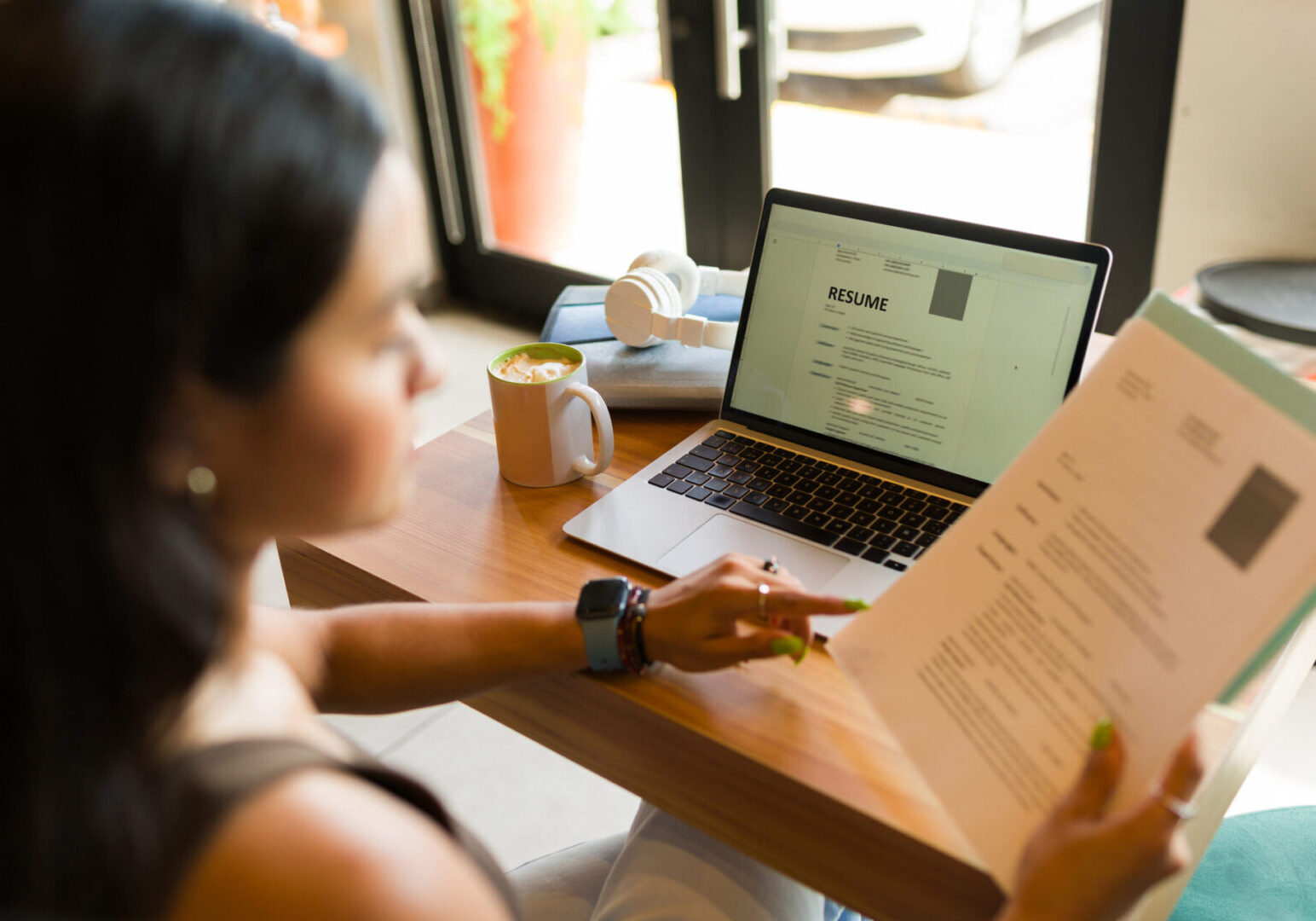 Young woman looking for a new job and sending her online CV resume using the internet zone of the coffee shop