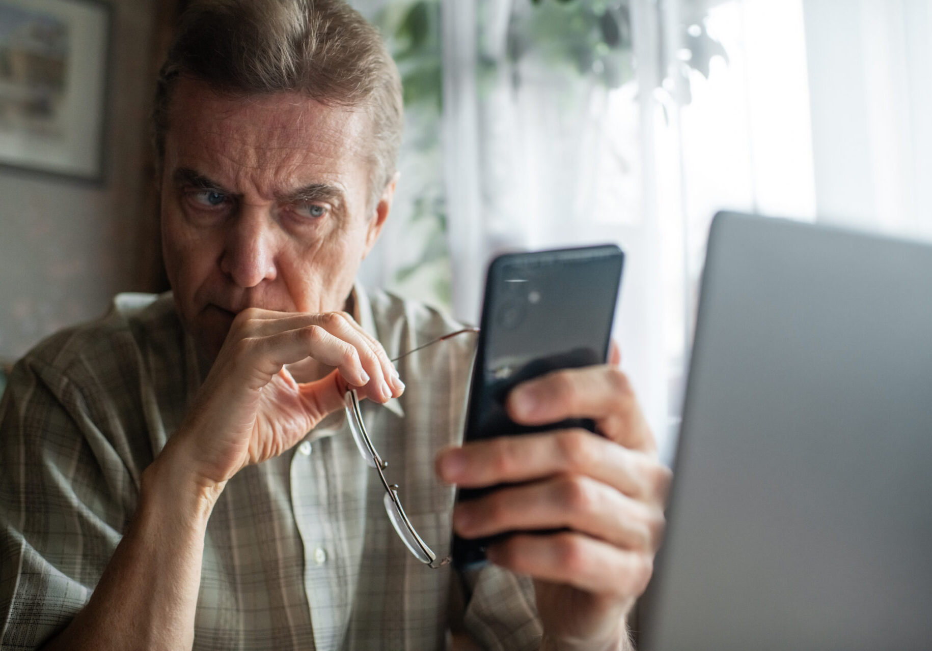 Senior man looking seriously at smartphone