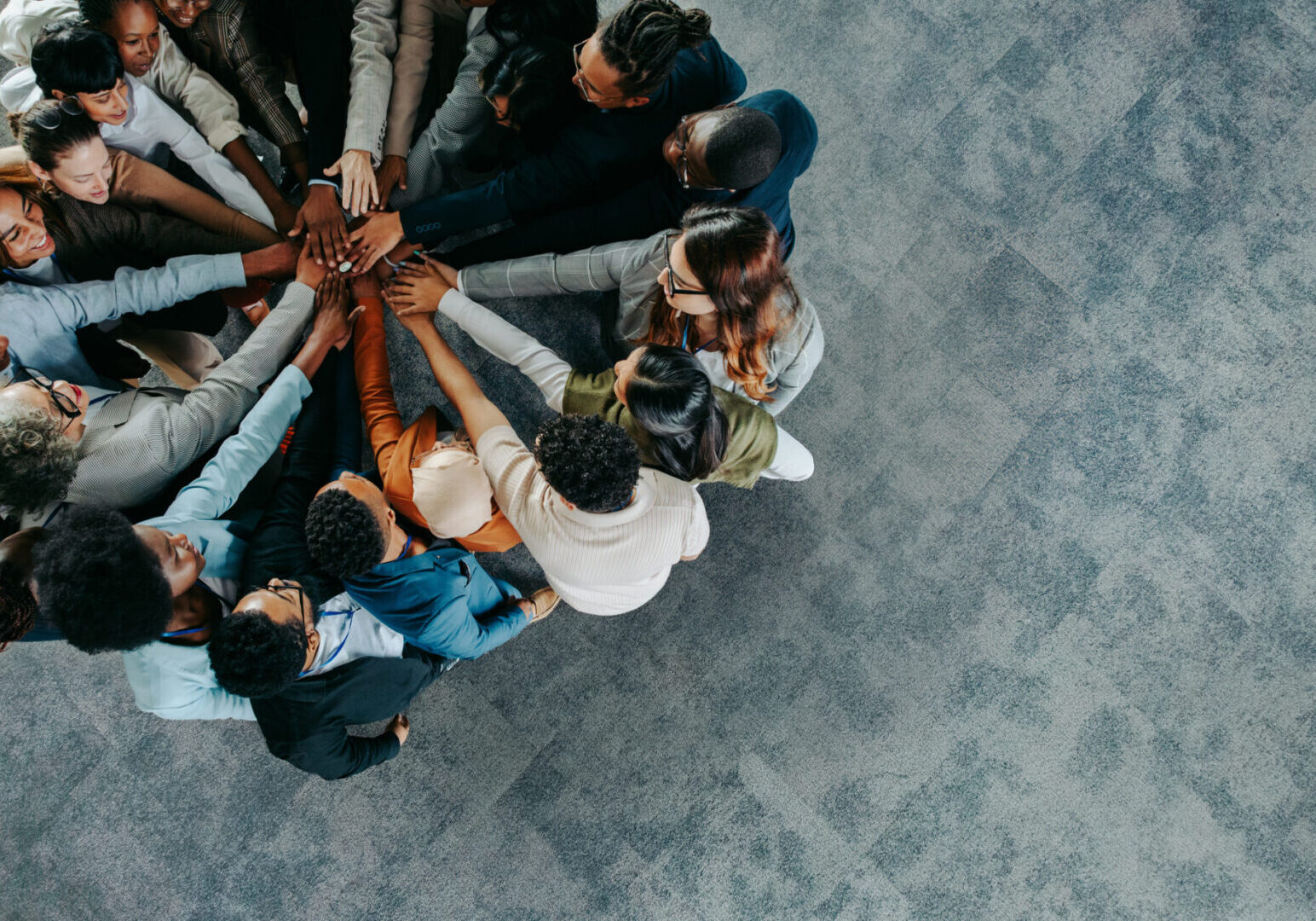 A diverse business team showing collaboration and unity with hands joined together in a team-building exercise.